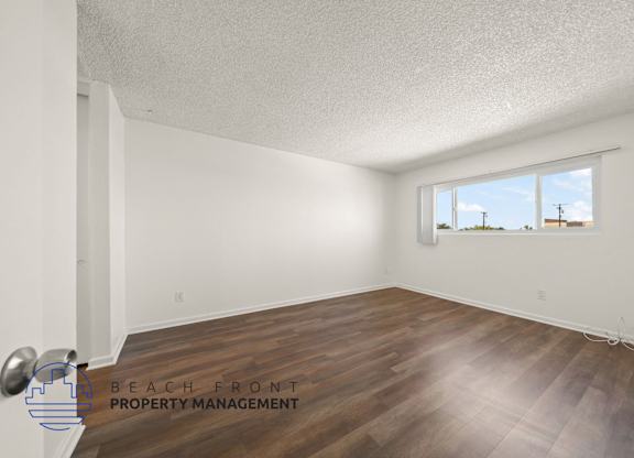 A room with a window and wooden flooring.