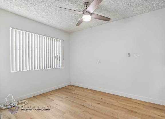 A room with a ceiling fan and wooden flooring.