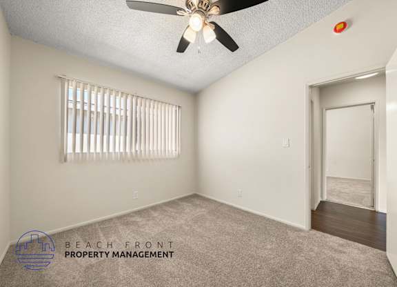 A room with a ceiling fan and a window with blinds.