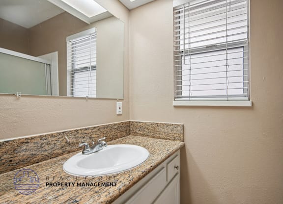 A bathroom with a granite countertop and a large mirror.
