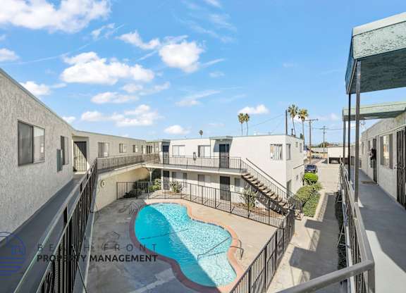 A pool is surrounded by a fence and a building.