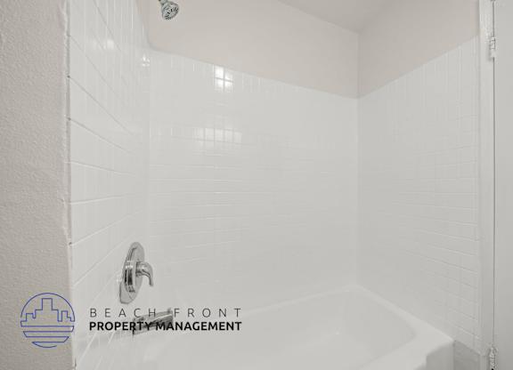 A white bathroom with a shower and a faucet.