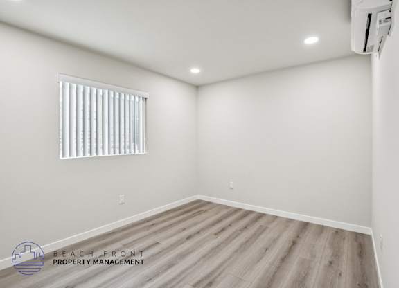 A room with a window and wooden flooring.
