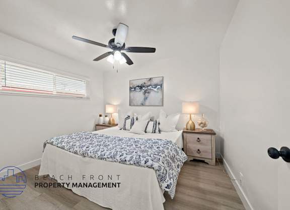 A bedroom with a bed, nightstands, and a ceiling fan.