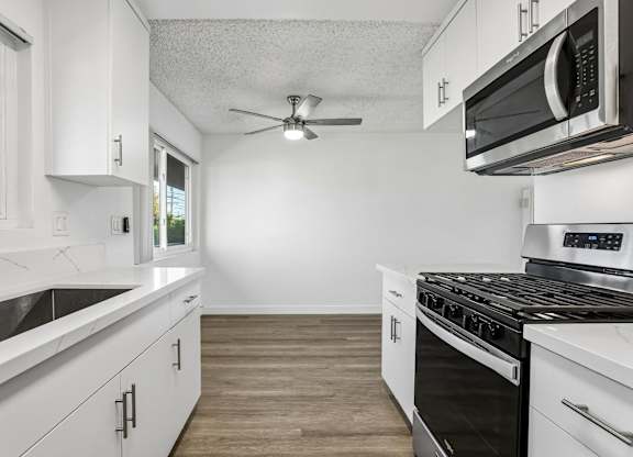 A modern kitchen with white cabinets and stainless steel appliances.