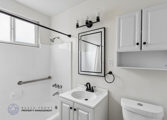 A bathroom with a sink, toilet, and mirror.