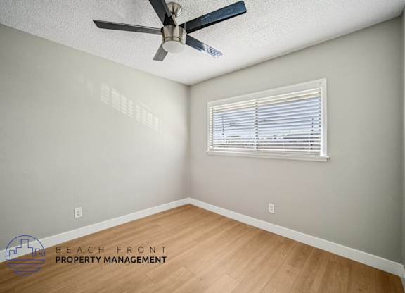A room with a ceiling fan and a window with blinds.
