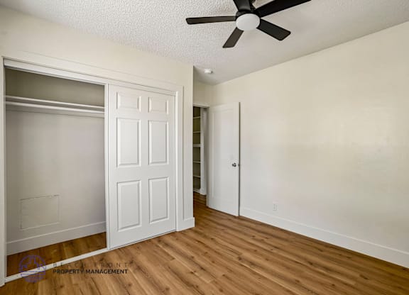 A room with a ceiling fan and a door.