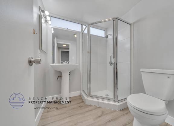A white toilet sits next to a walk-in shower with a glass door.
