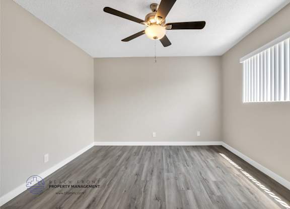 A room with a ceiling fan and wooden flooring.