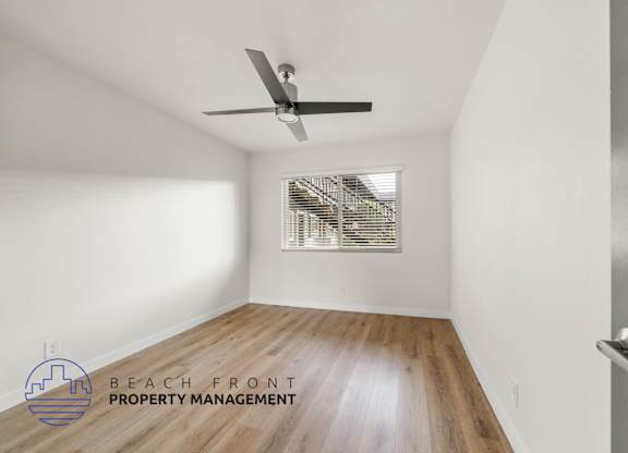 A room with a ceiling fan and wooden flooring.