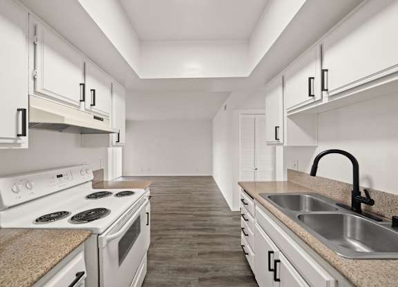 A kitchen with white cabinets and a white stove top oven.