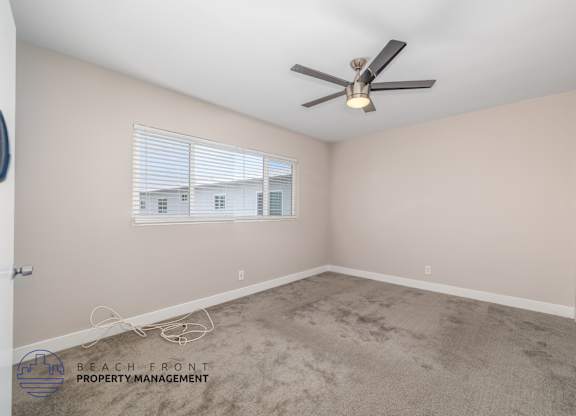 A room with a ceiling fan and a window with blinds.