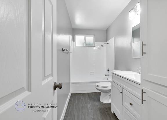 A white bathroom with a toilet, sink, and mirror.