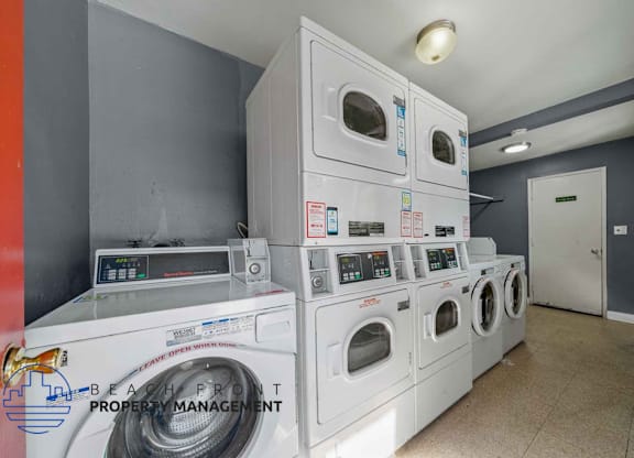 A stack of white front load washing machines in a laundry room.