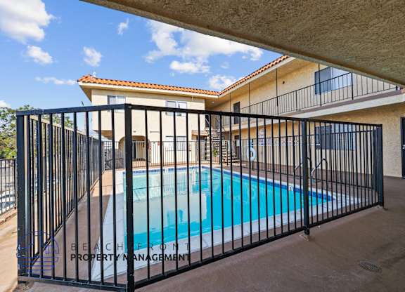 a swimming pool behind a wrought iron fence in front of a house