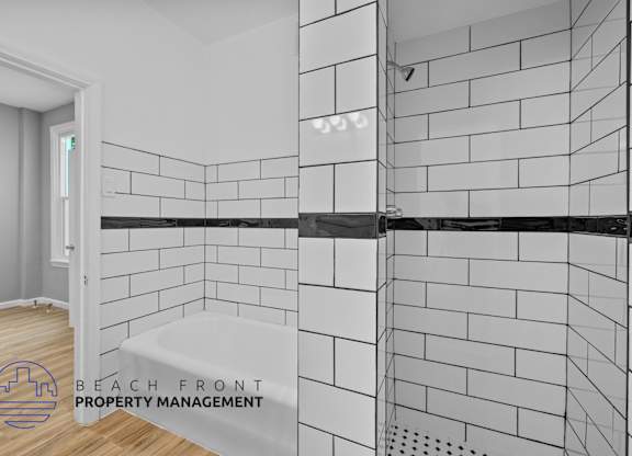 a white tiled shower in a bathroom with a wood floor