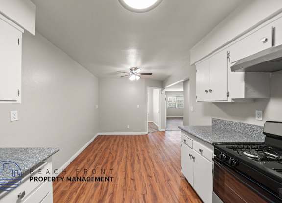 A kitchen with wooden floors and white cabinets.