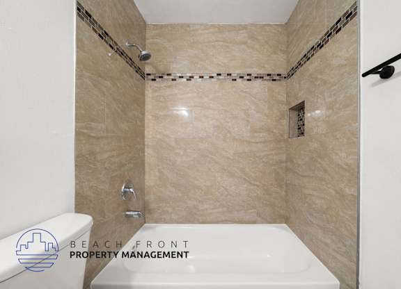 A bathroom with beige tiles and a white tub.