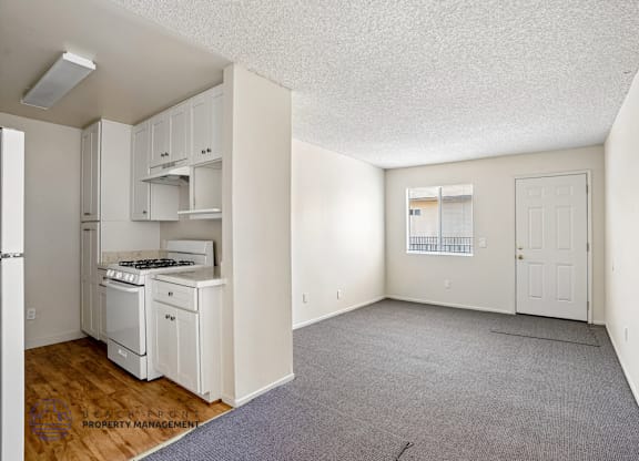 A small, empty room with a kitchenette and a door leading to another room.