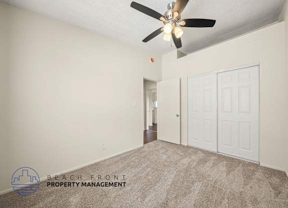 A room with a carpet floor and a ceiling fan.