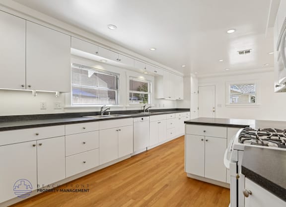 A modern kitchen with white cabinets and a black countertop.
