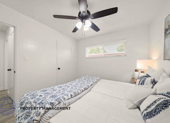 A bedroom with a bed, pillows, and a ceiling fan.
