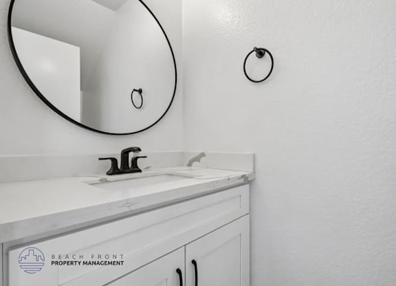 A bathroom sink with a round mirror above it.