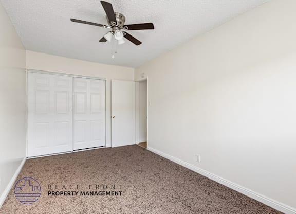 A room with a ceiling fan and carpeted floor.