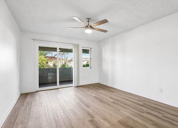 A room with a ceiling fan and sliding glass doors.