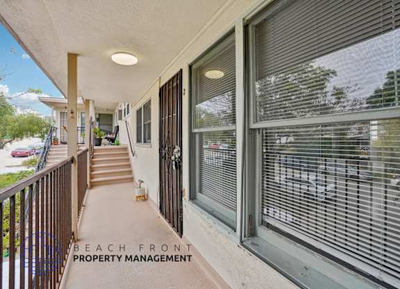 A balcony with a view of the beach and a sign for Beach Front Property Management.