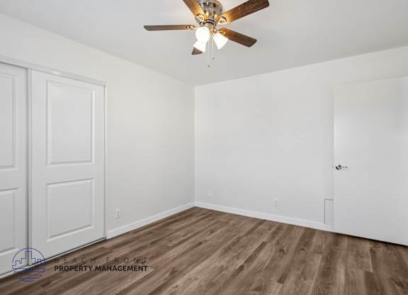 A room with a ceiling fan and wooden flooring.