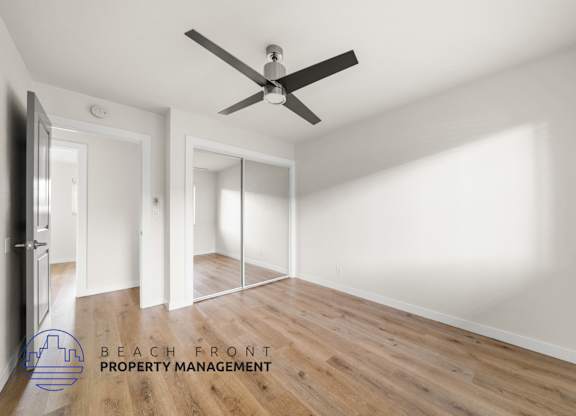 A room with a ceiling fan and wooden flooring.