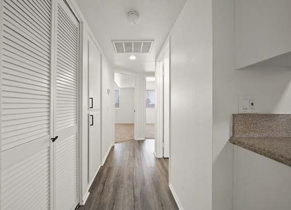 A long hallway with white walls and wood flooring.