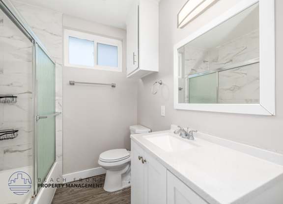 A white bathroom with a toilet, sink, and mirror.
