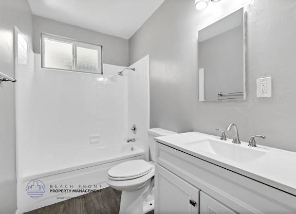 A white bathroom with a toilet, sink, and mirror.