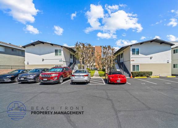 a parking lot with cars parked in front of apartment buildings