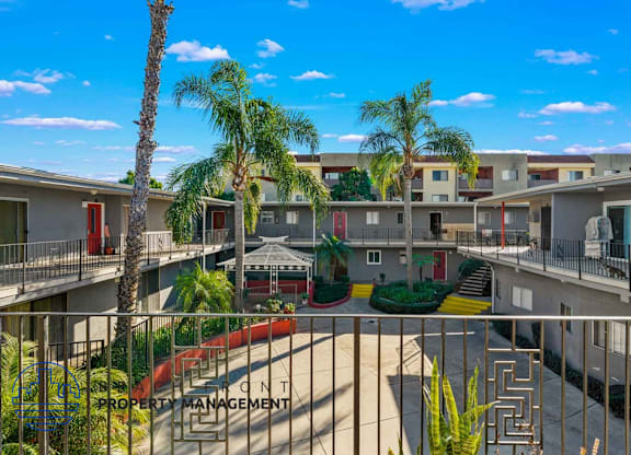 A sunny day at the property management building with palm trees and a clear blue sky.