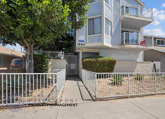 A modern two-story house with a white fence in front.