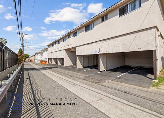 A street view of a residential area with apartment buildings and a clear sky.