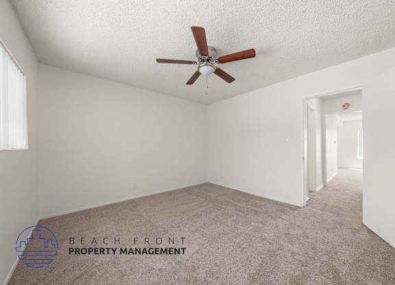A room with a ceiling fan and carpeted floor.