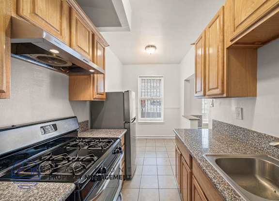 A kitchen with a stove top oven and a refrigerator.