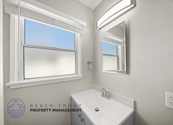 A bathroom with a large window and a white sink.