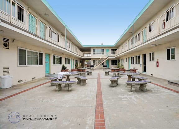 A courtyard with tables and benches surrounded by buildings.