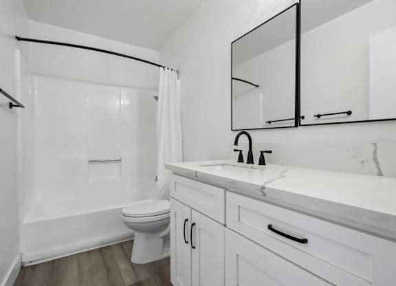 A white bathroom with a toilet, sink, and mirror.