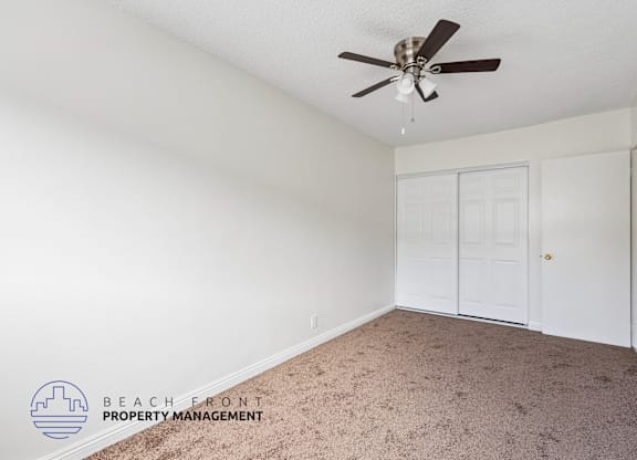 A room with a carpet floor and a ceiling fan.