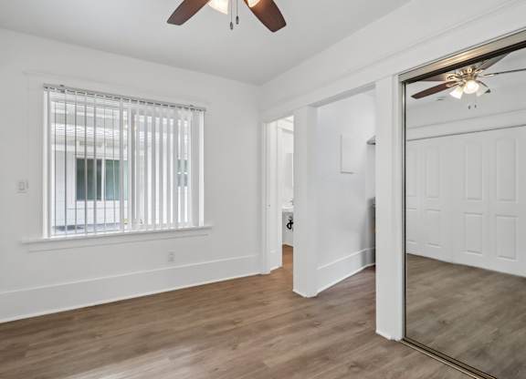 A room with a ceiling fan and a window with blinds.