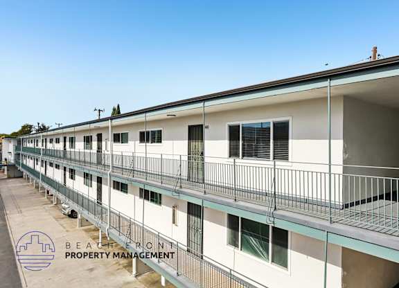 A row of white buildings with balconies and the logo of Beachfront Property Management in the bottom left corner.