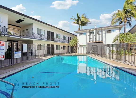 A swimming pool in front of a building with the words Beach Front Property Management.