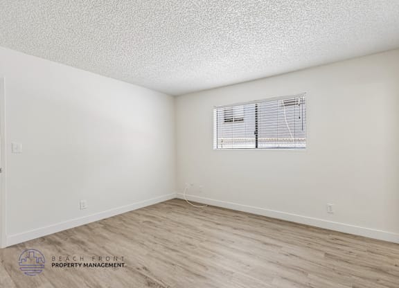 A room with a window and wooden flooring.